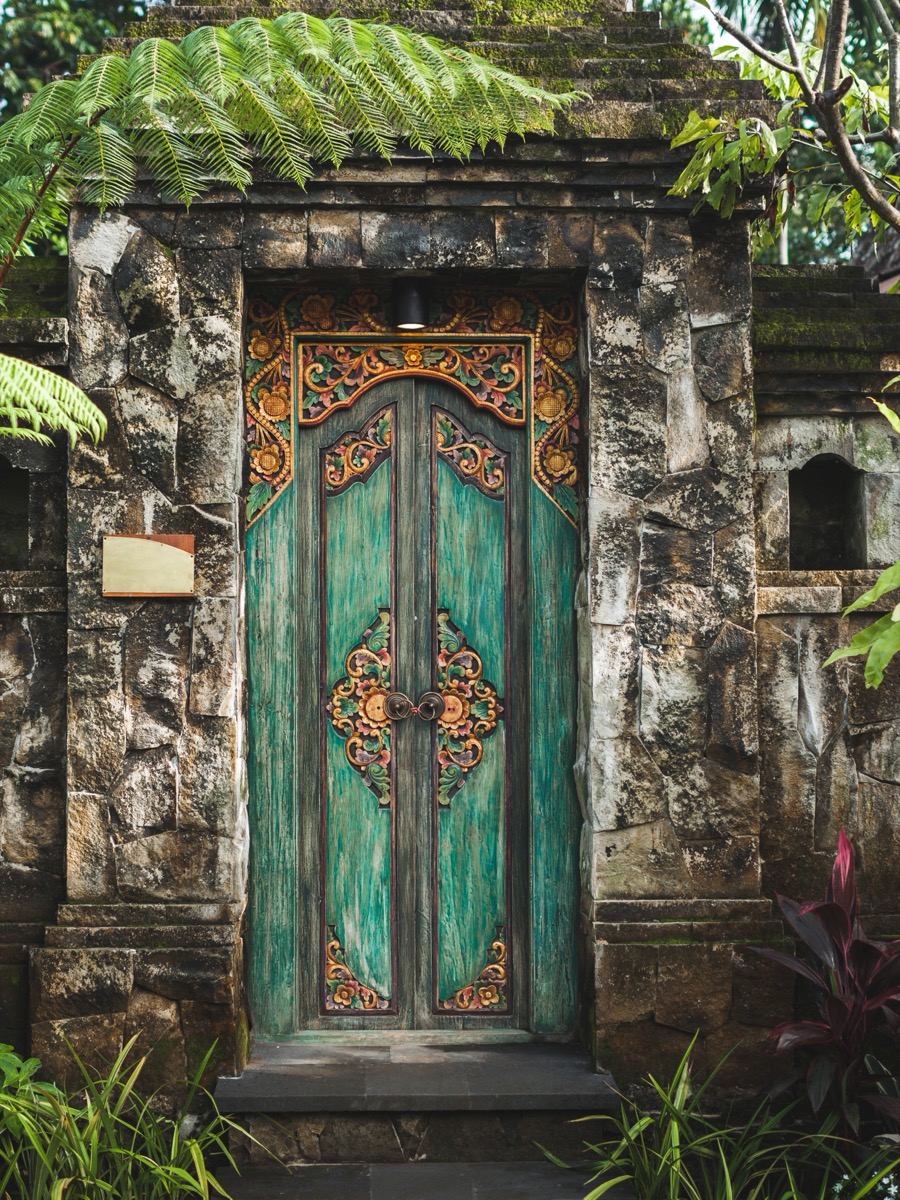 Bali'de geleneksel oymalı taş kapı ve tropik bitki örtüsü